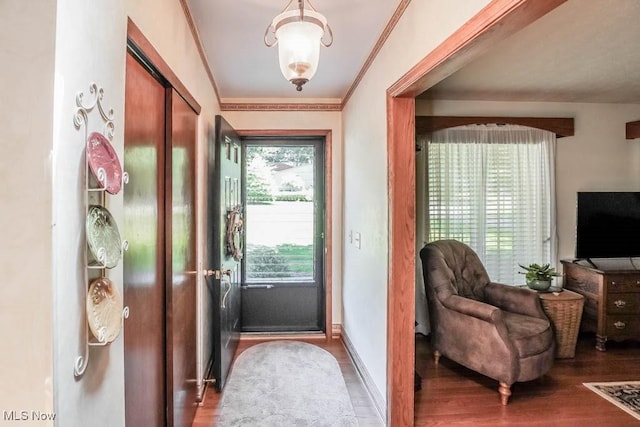 foyer entrance featuring baseboards, wood finished floors, and crown molding