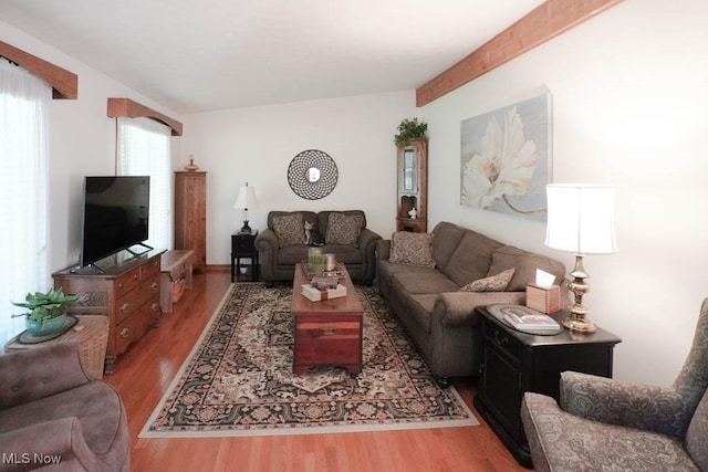 living area featuring vaulted ceiling with beams and wood finished floors