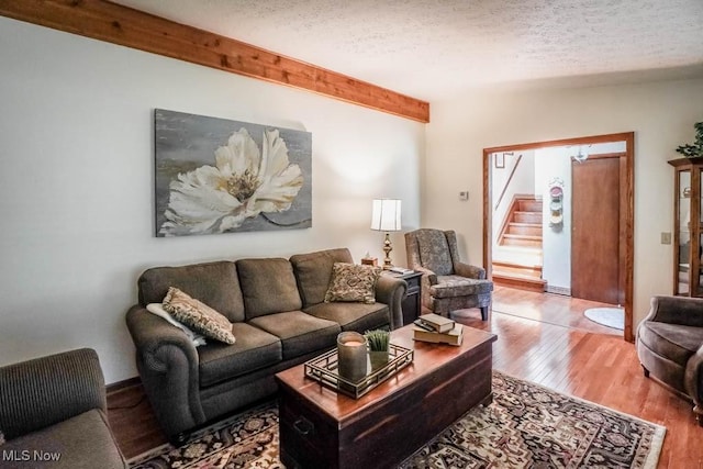 living area with stairs, wood finished floors, and a textured ceiling