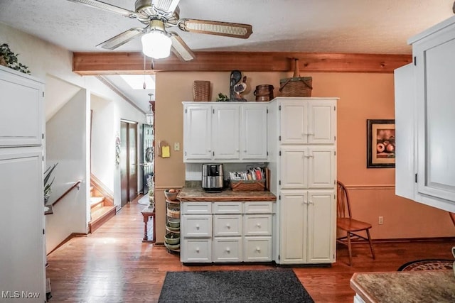 kitchen with a textured ceiling, wood finished floors, white cabinetry, ceiling fan, and vaulted ceiling with beams