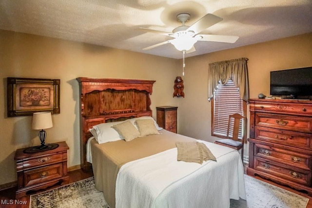 bedroom featuring ceiling fan, baseboards, a textured ceiling, and wood finished floors