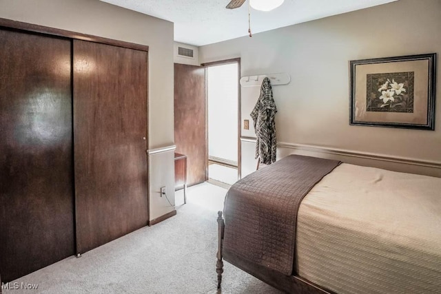 bedroom featuring a ceiling fan, visible vents, a closet, a textured ceiling, and light carpet