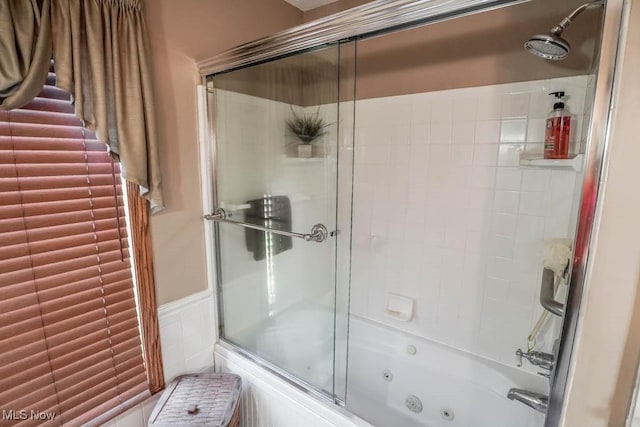 bathroom featuring wainscoting, tile walls, and a combined bath / shower with jetted tub