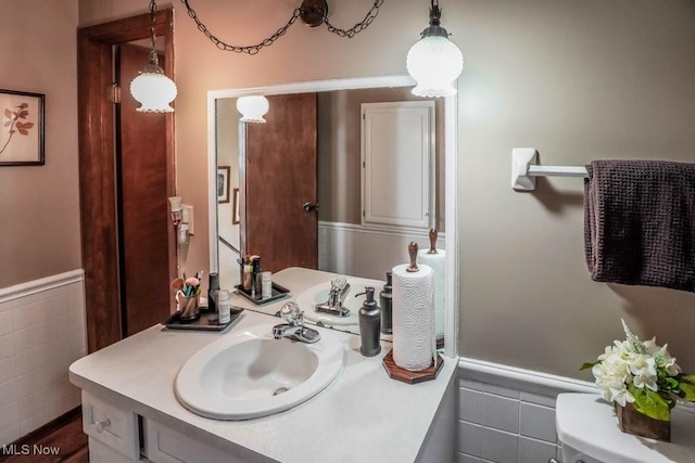 half bath featuring wainscoting, tile walls, and vanity