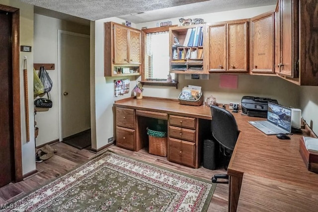 office space featuring baseboards, wood finished floors, built in desk, and a textured ceiling