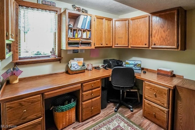 office space with a textured ceiling, wood finished floors, and built in study area