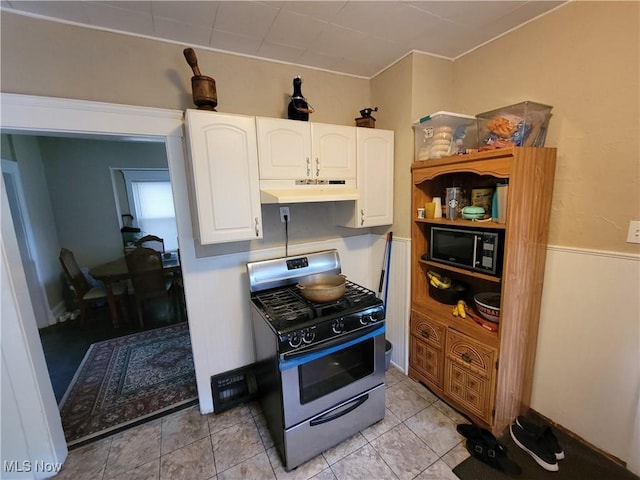 kitchen featuring light tile patterned floors, white cabinets, under cabinet range hood, black microwave, and stainless steel gas stove