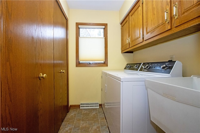 clothes washing area featuring a sink, baseboards, cabinet space, and washer and clothes dryer