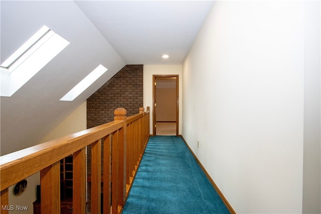 corridor with lofted ceiling with skylight, carpet flooring, an upstairs landing, and baseboards