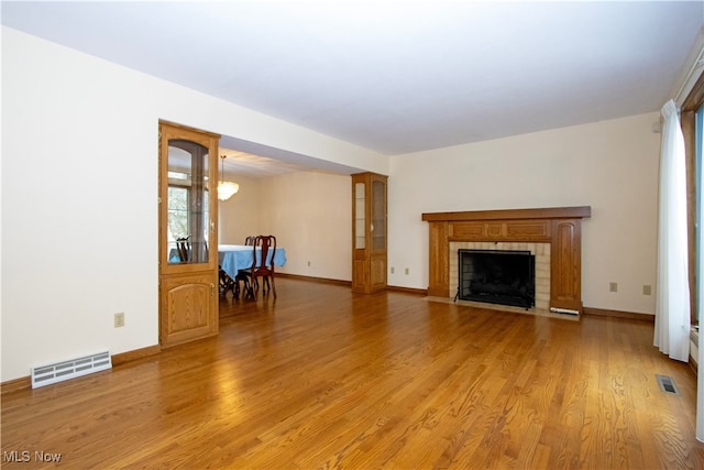 unfurnished living room with visible vents, baseboards, light wood-style floors, and a fireplace with flush hearth