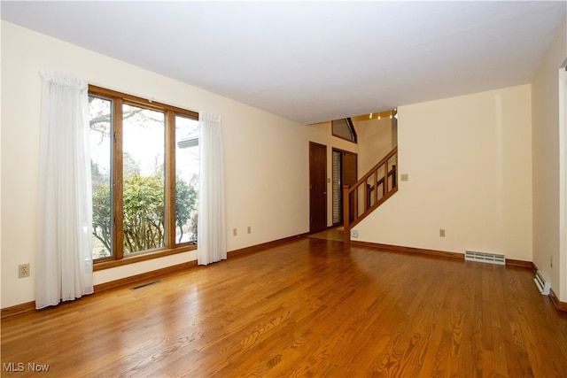 unfurnished room featuring plenty of natural light, wood finished floors, and visible vents