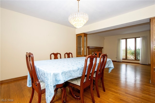 dining area featuring an inviting chandelier, baseboards, and light wood-type flooring