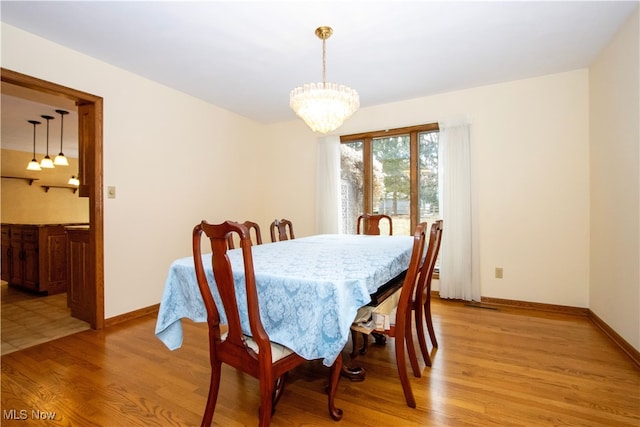 dining area featuring a notable chandelier, baseboards, and light wood finished floors