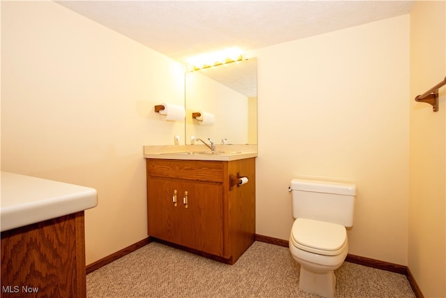 bathroom featuring toilet, vanity, and baseboards