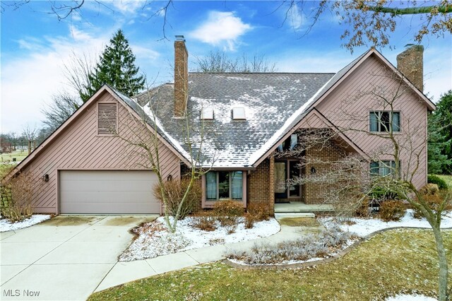 view of front of property with concrete driveway, an attached garage, brick siding, and a chimney