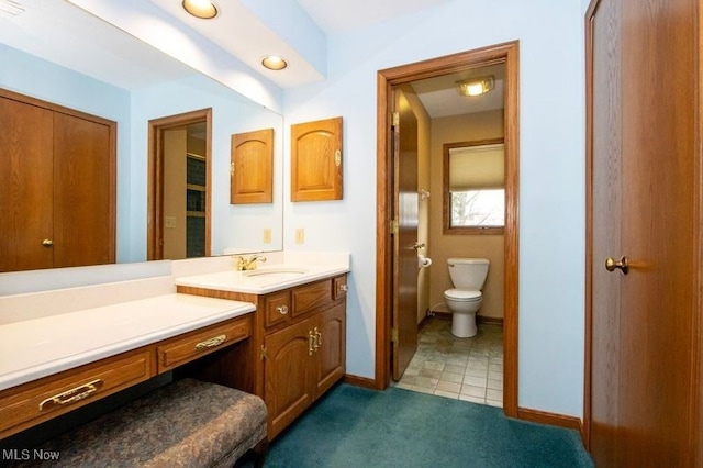 bathroom featuring toilet, vanity, and baseboards