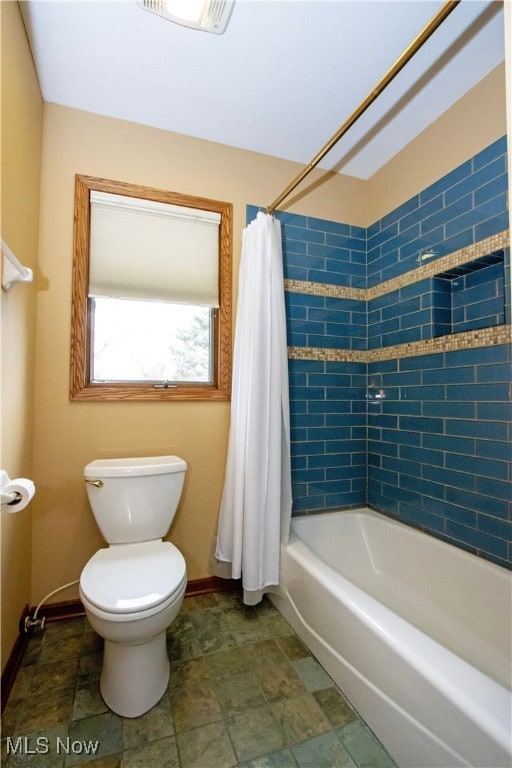 full bath with visible vents, stone finish flooring, baseboards, toilet, and shower / tub combo