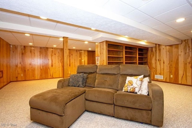 carpeted living room with wooden walls, visible vents, baseboards, recessed lighting, and a paneled ceiling