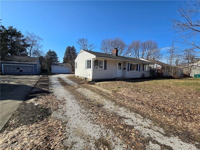 view of front of house with driveway, a chimney, and an outdoor structure