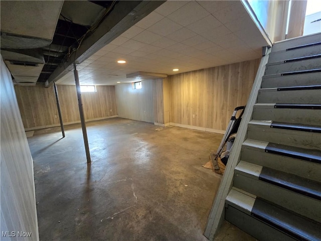 below grade area with stairway, wooden walls, and baseboards