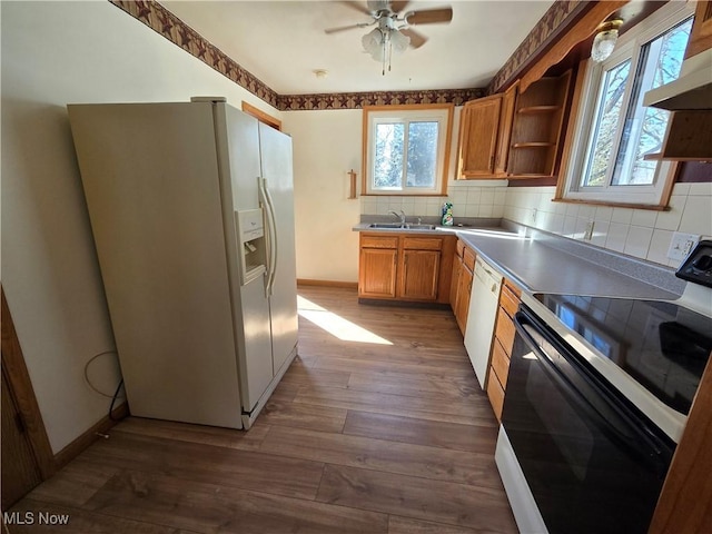 kitchen featuring dark wood-type flooring, a sink, open shelves, white appliances, and wall chimney exhaust hood