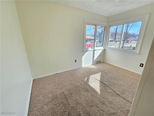 carpeted empty room featuring visible vents and baseboards