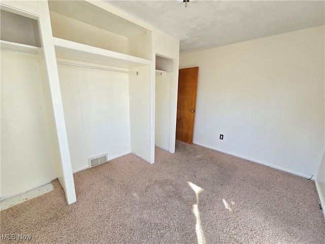 unfurnished bedroom featuring a closet, visible vents, and carpet