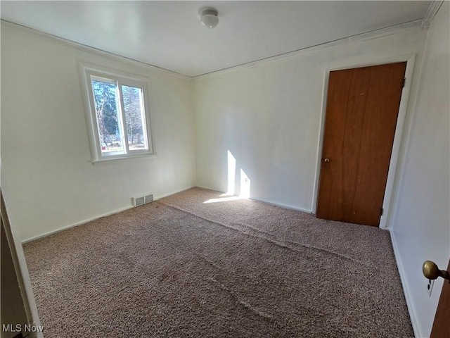 spare room featuring visible vents, carpet floors, and ornamental molding