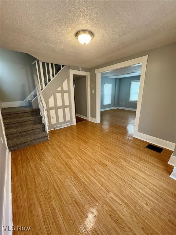 interior space featuring stairway, baseboards, visible vents, and light wood-type flooring