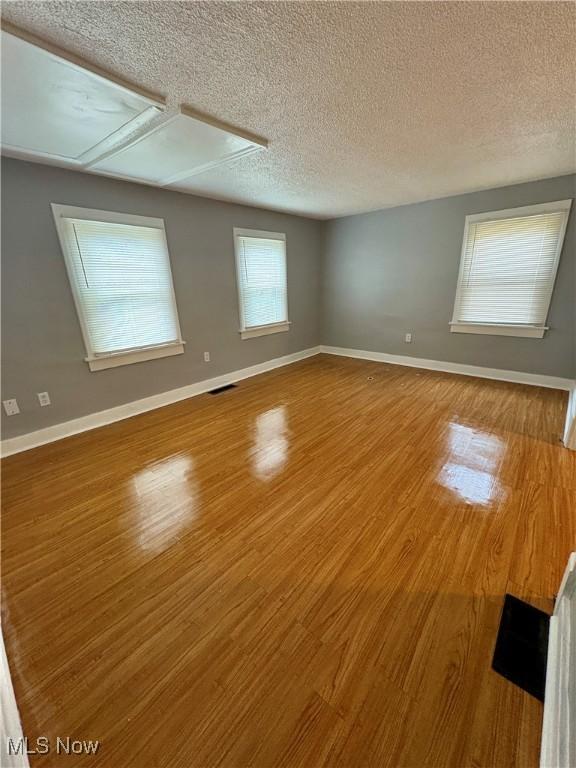 spare room featuring visible vents, baseboards, and wood finished floors