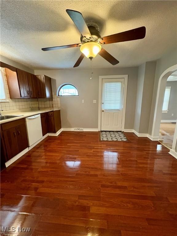 kitchen featuring ceiling fan, dishwasher, dark wood-style floors, decorative backsplash, and arched walkways