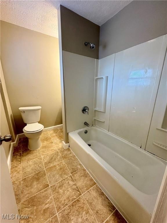 bathroom with baseboards, toilet, shower / tub combination, and a textured ceiling