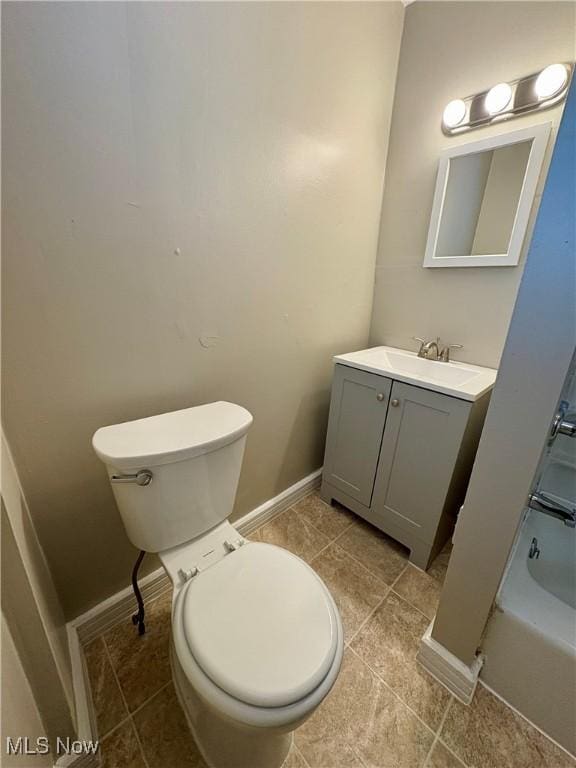 bathroom with vanity, baseboards, tub / shower combination, tile patterned flooring, and toilet