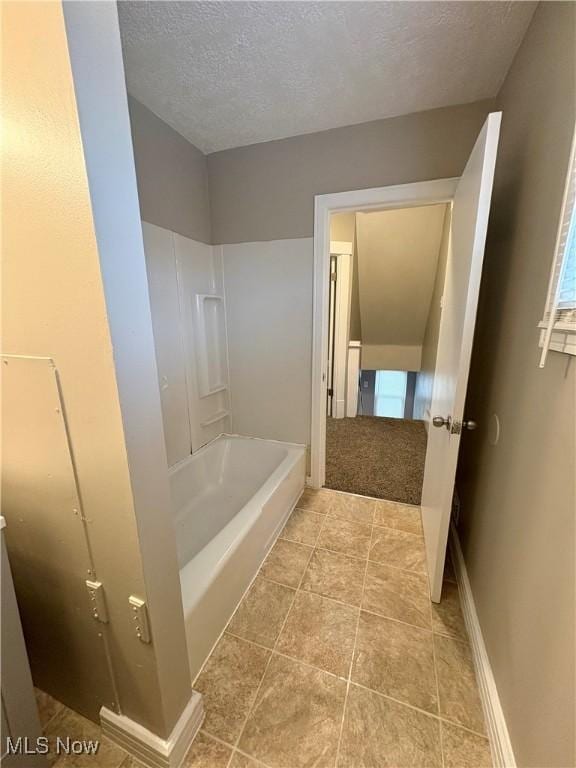 bathroom with shower / bathing tub combination, baseboards, and a textured ceiling