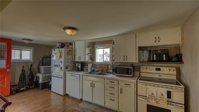 kitchen featuring light wood-type flooring, white appliances, plenty of natural light, and light countertops