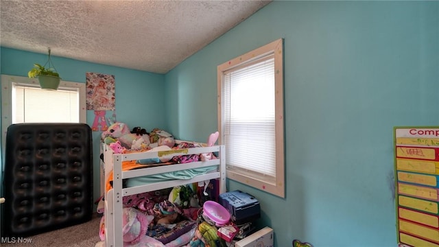 carpeted bedroom with multiple windows and a textured ceiling