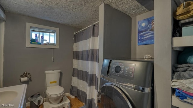 bathroom with a shower with curtain, toilet, a textured ceiling, wood finished floors, and washer / dryer