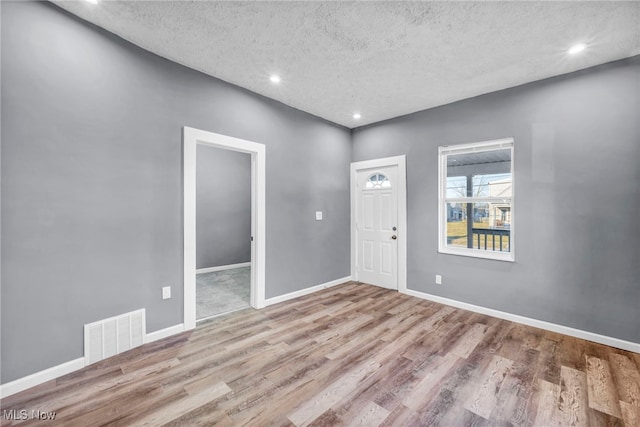 foyer entrance featuring wood finished floors, visible vents, baseboards, recessed lighting, and a textured ceiling