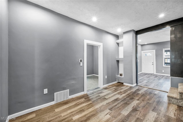 empty room featuring visible vents, recessed lighting, baseboards, and wood finished floors