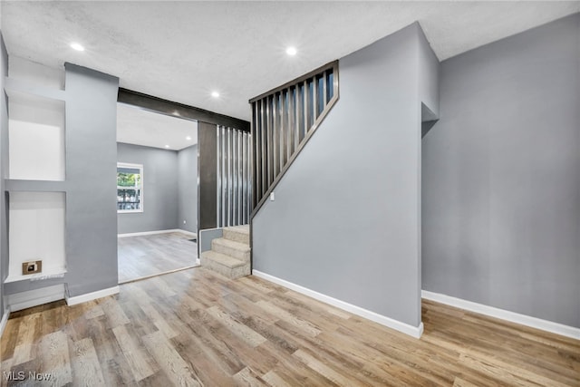 unfurnished living room featuring stairway, recessed lighting, wood finished floors, and baseboards