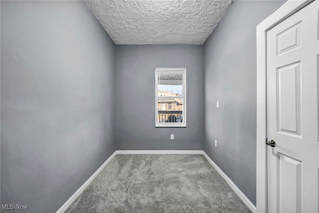 empty room with baseboards, carpet, and a textured ceiling