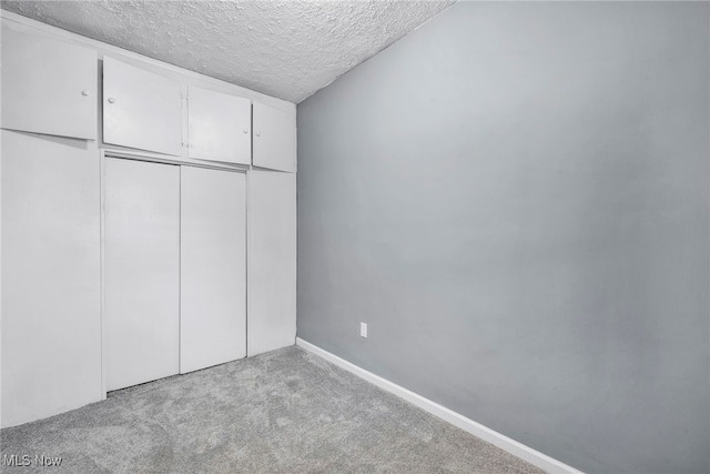 unfurnished bedroom with a closet, baseboards, carpet, and a textured ceiling