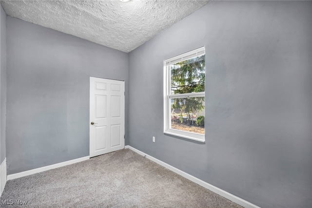 unfurnished room with carpet, baseboards, and a textured ceiling