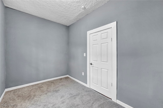 unfurnished room with baseboards, carpet, and a textured ceiling