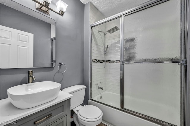 bathroom with combined bath / shower with glass door, toilet, and vanity