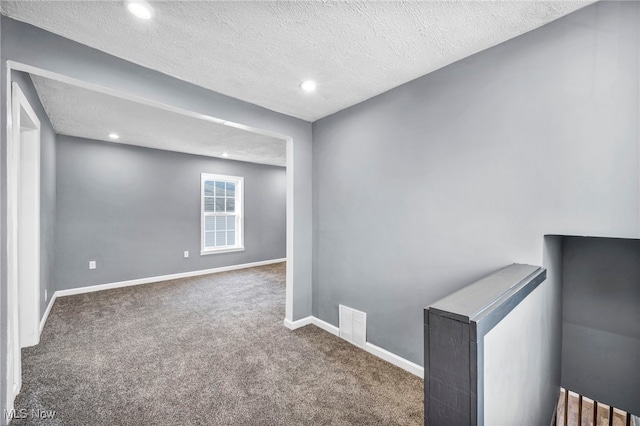 empty room featuring visible vents, a textured ceiling, recessed lighting, carpet flooring, and baseboards