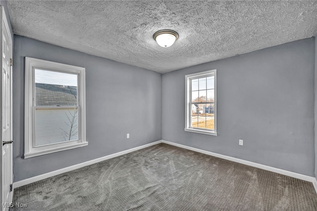 carpeted spare room featuring baseboards and a textured ceiling