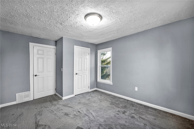 unfurnished bedroom with visible vents, a textured ceiling, a closet, carpet floors, and baseboards