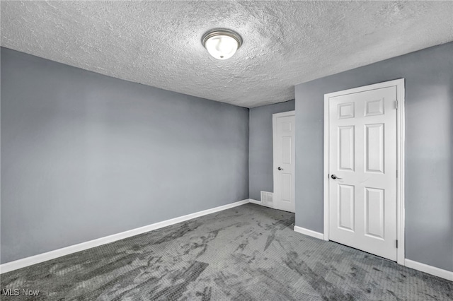 unfurnished bedroom featuring visible vents, a textured ceiling, baseboards, and carpet