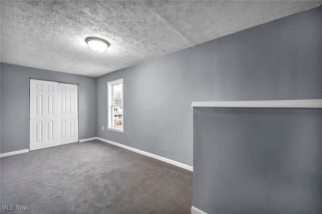 unfurnished bedroom featuring a closet, a textured ceiling, baseboards, and dark colored carpet